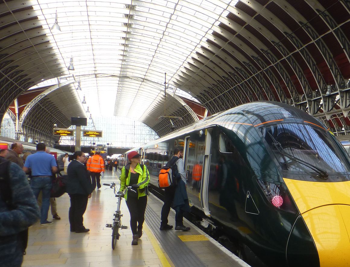 Commuters on the platform beside a train at London Paddington